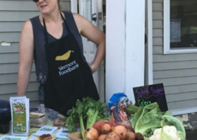 Woman Standing at an open house with tray of vegetables.